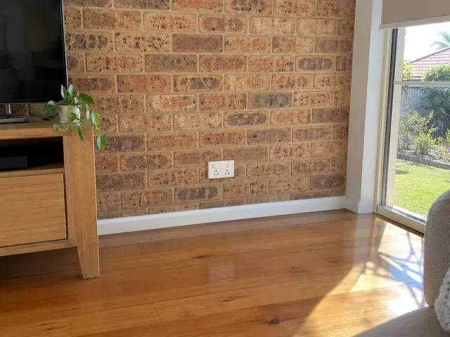 White double power point on a brick feature wall beside timber flooring and a window in Reedy Creek